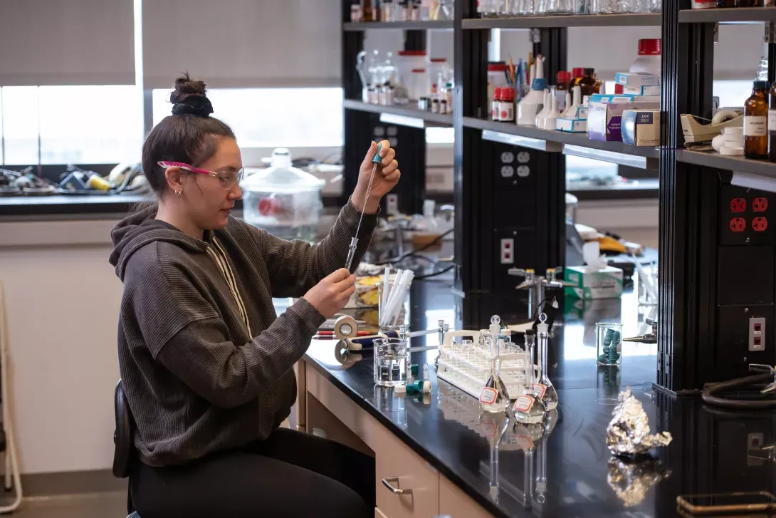 Student using pipette to transfer chemicals in chemistry lab